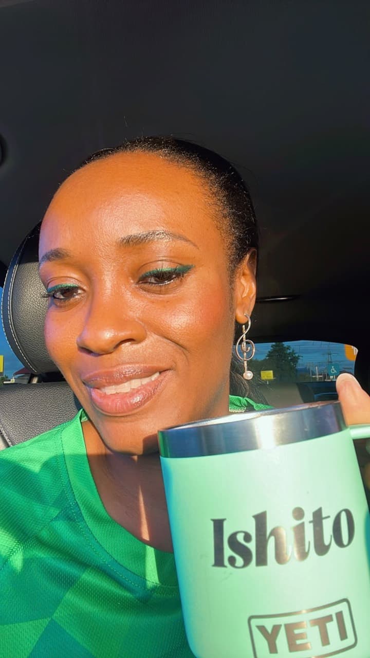 Mmayen Assam smiling with a cup of tea and a treble-clef earring